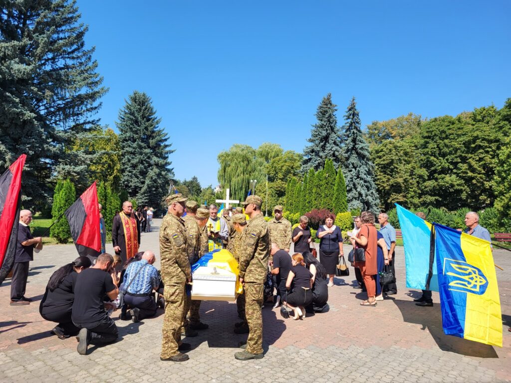 Українські військові на похороні з прапорами України.