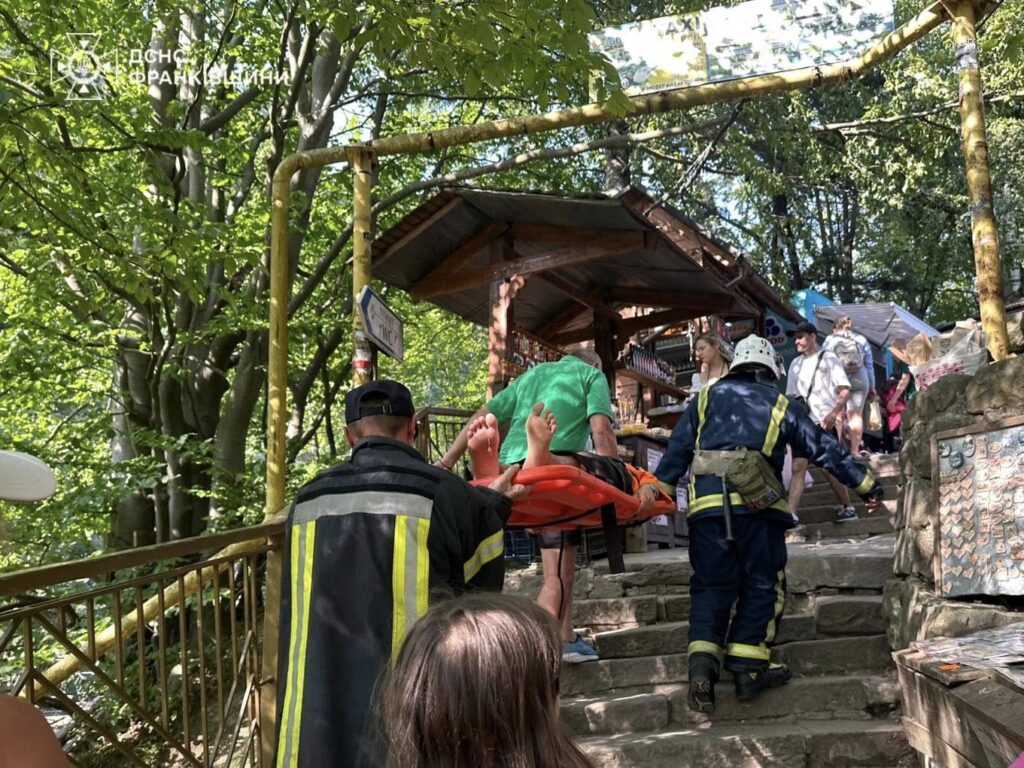 Рятувальники несуть потерпілого на носилках в лісі.