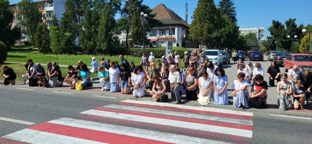Люди на колінах біля пішохідного переходу.