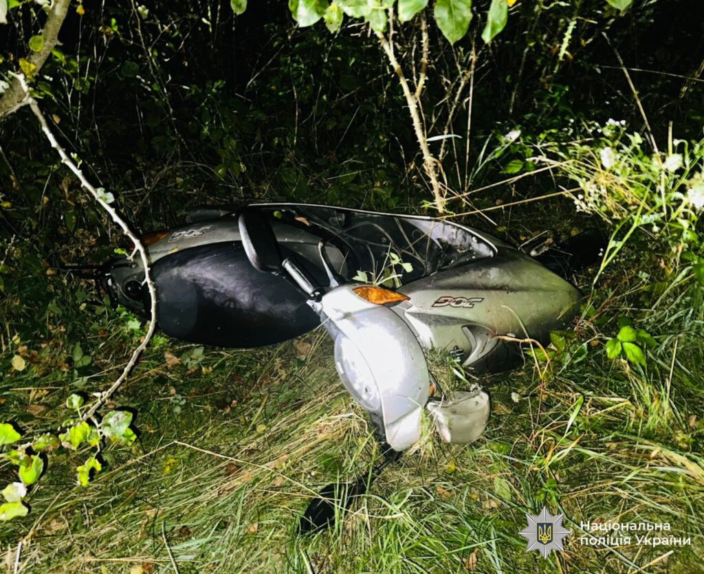 Мопед у траві біля узлісся вночі.