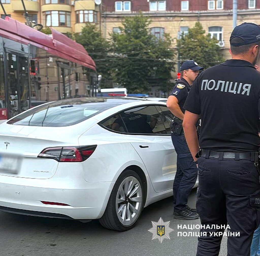Поліція біля білого авто на вулиці.