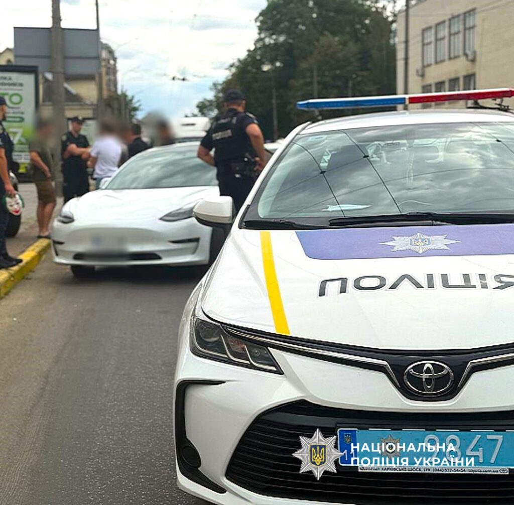 Поліцейська машина на міській вулиці, поруч автомобіль.