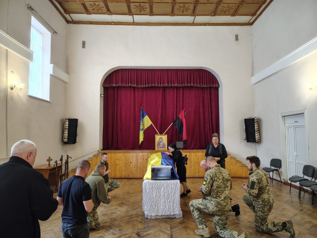 Вшанування героїв в актовій залі з прапорами.