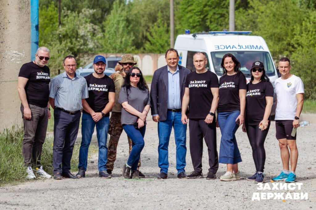Група людей перед автомобілем швидкої допомоги