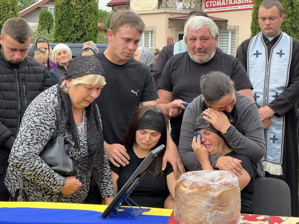 Сумні люди прощаються з близьким на похороні.