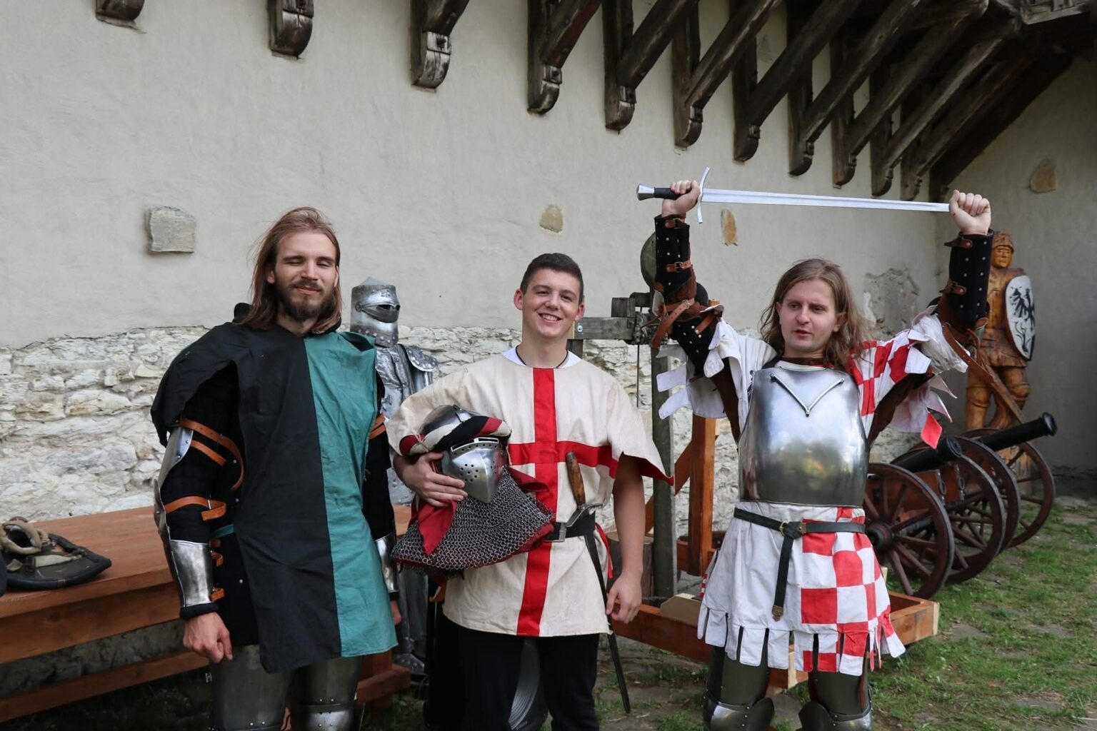 Троє лицарів у середньовічних костюмах, один з мечем.