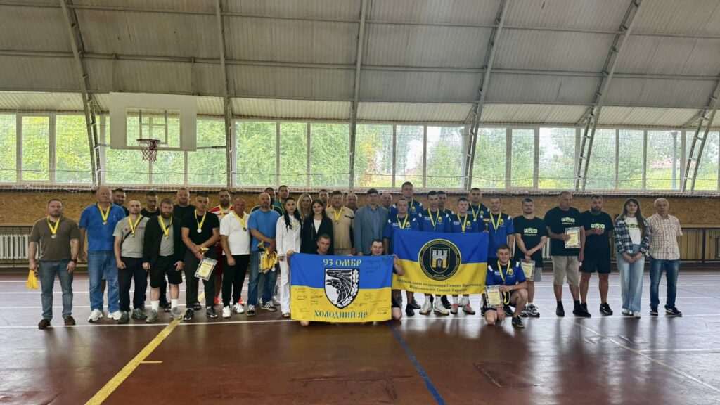 Групове фото команди з прапорами та медалями.