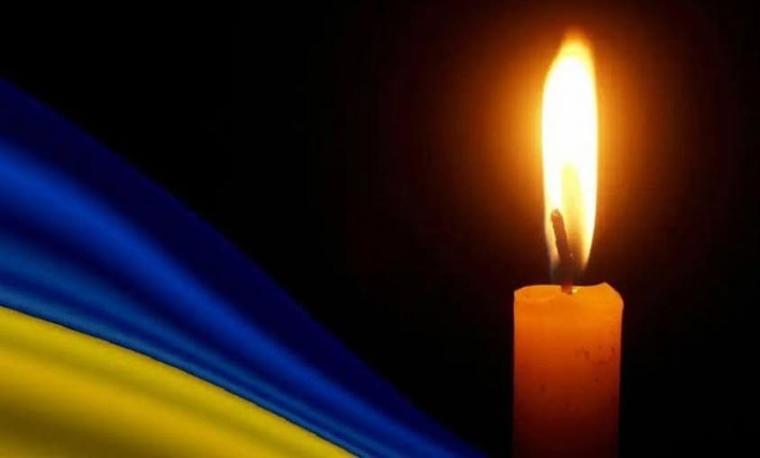 Свічка пам'яті поруч з прапором України