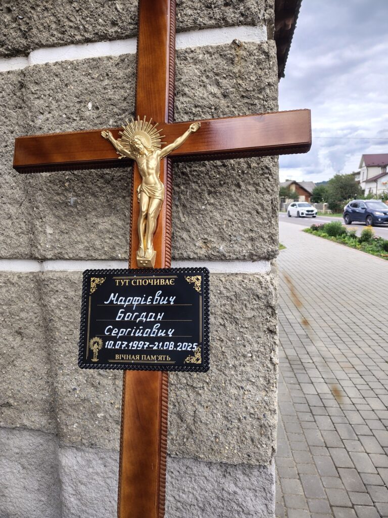 Надгробний хрест з табличкою на вулиці.