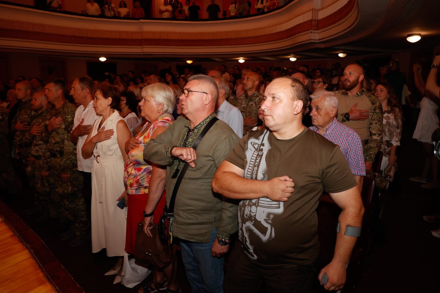 Люди під час церемонії з рукою на грудях.