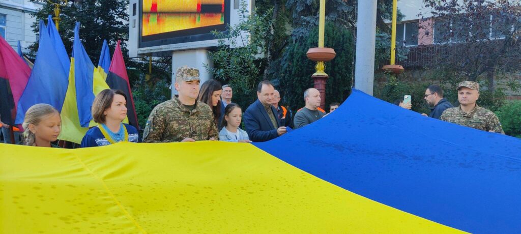 Люди тримають великий прапор України на вулиці.