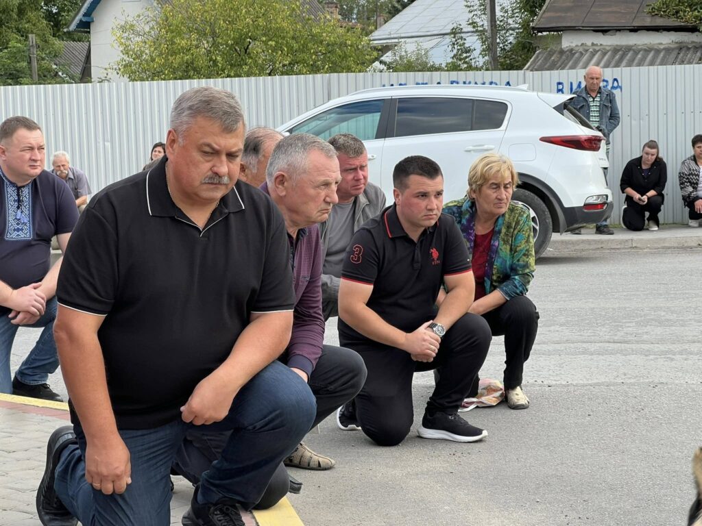 Люди стоять на одному коліні на вулиці.