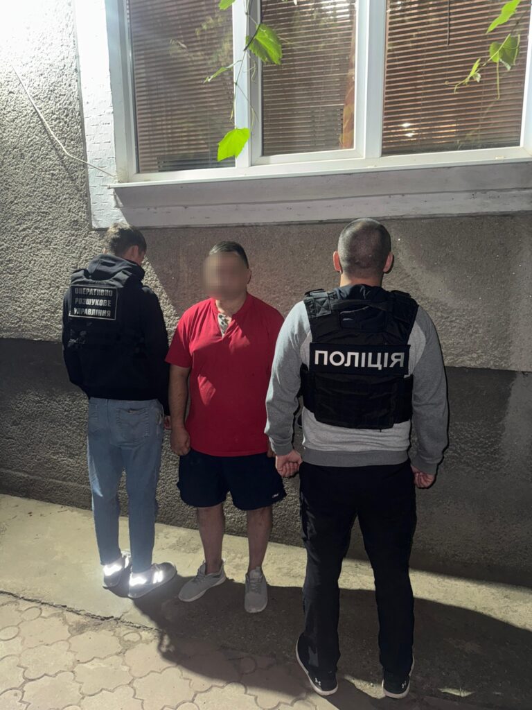 Поліцейські затримують чоловіка біля будівлі вночі.