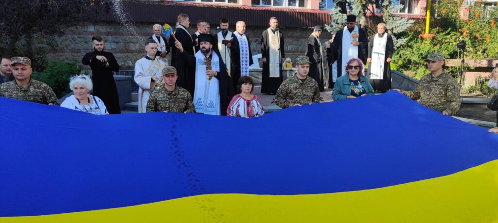 Люди з українським прапором на міському заході.