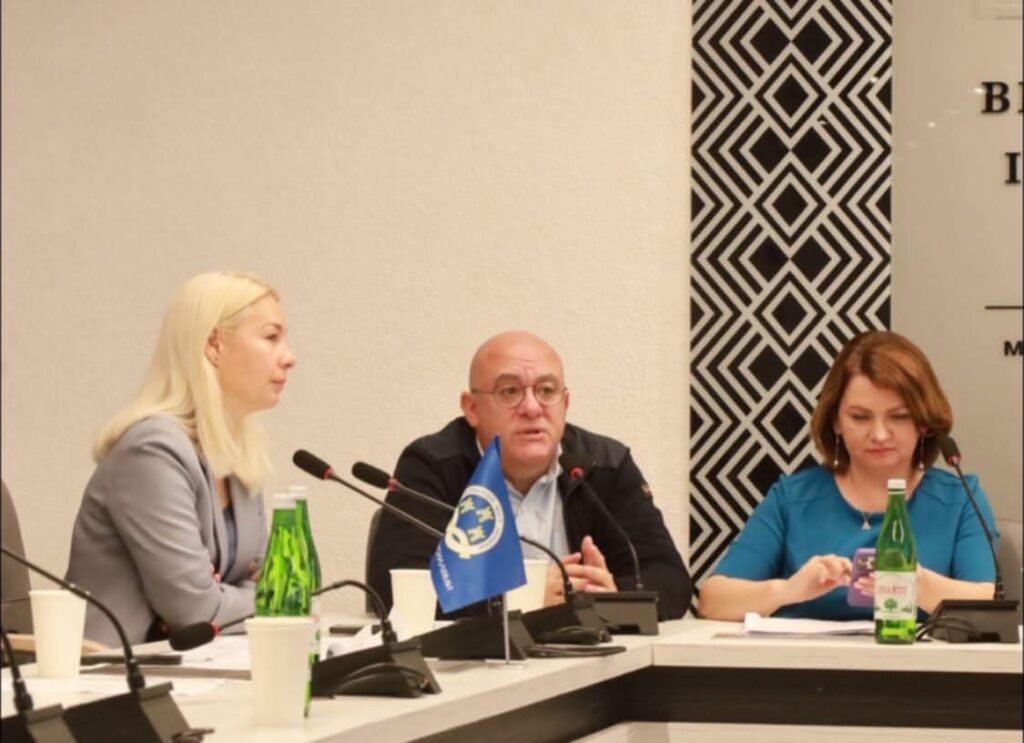 Люди на конференції за столом з мікрофонами.