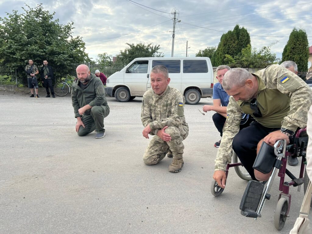Військові на дорозі, поруч білий мікроавтобус.