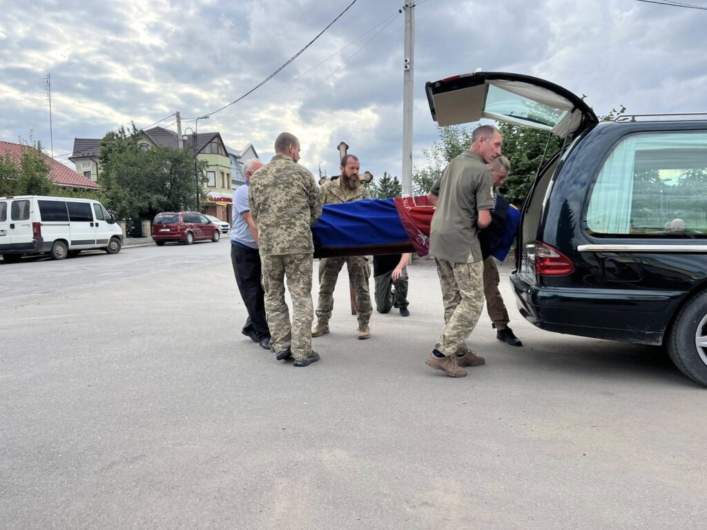 Військові несуть труну до похоронного авто.