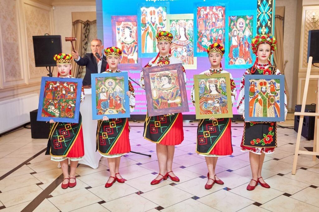 Українські танцівниці тримають картини на виставці