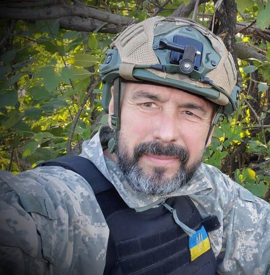 Військовий у камуфляжі і шоломі на фоні дерев.