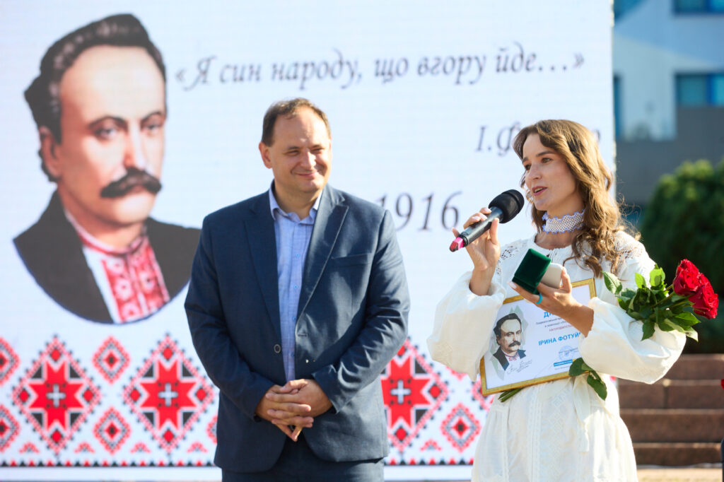 Жінка з нагородою промовляє на офіційному заході.