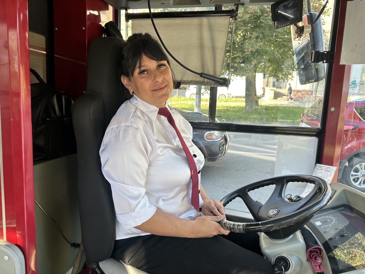 Водійка автобуса в біло-червоній уніформі