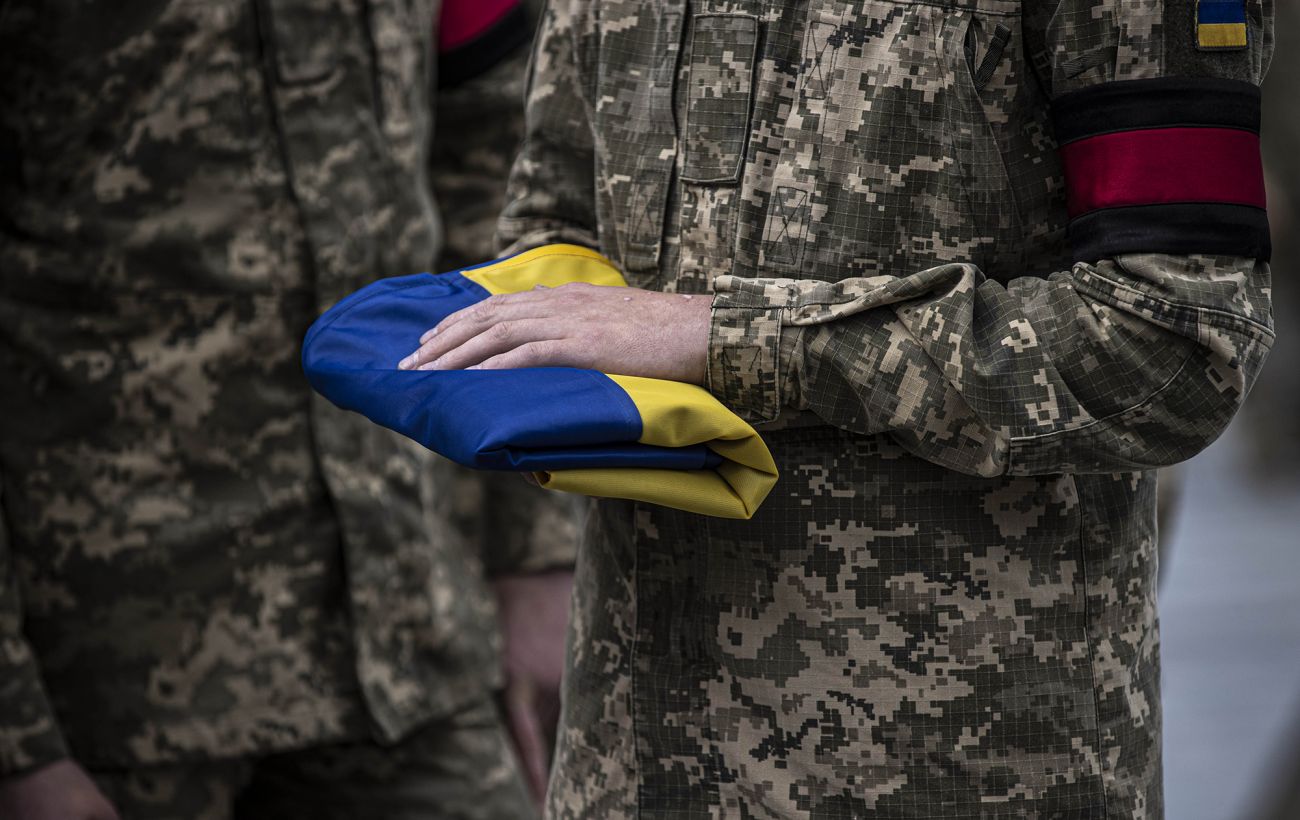 Військовий тримає складений український прапор