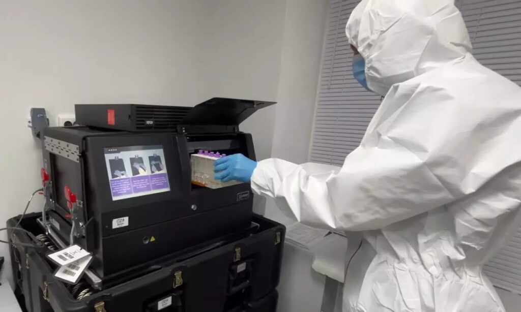 Лаборант використовує лабораторне обладнання в захисному костюмі.