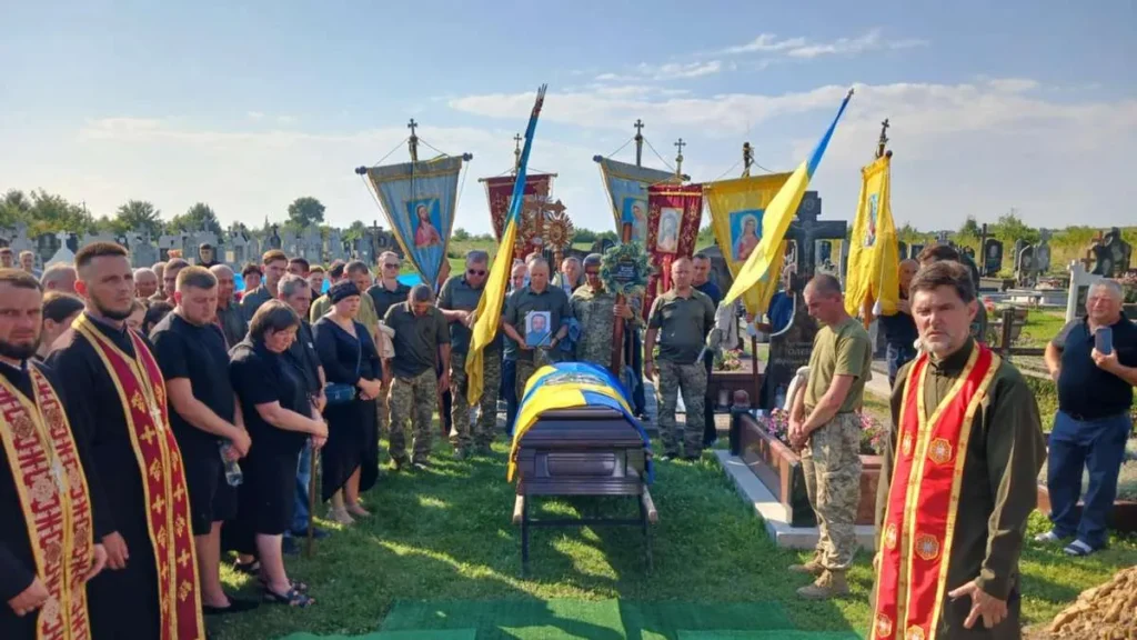 Похорон українського військовослужбовця з державними прапорами.