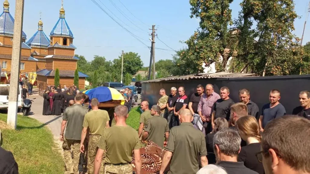 Прощальна церемонія біля дерев'яної церкви в Україні.
