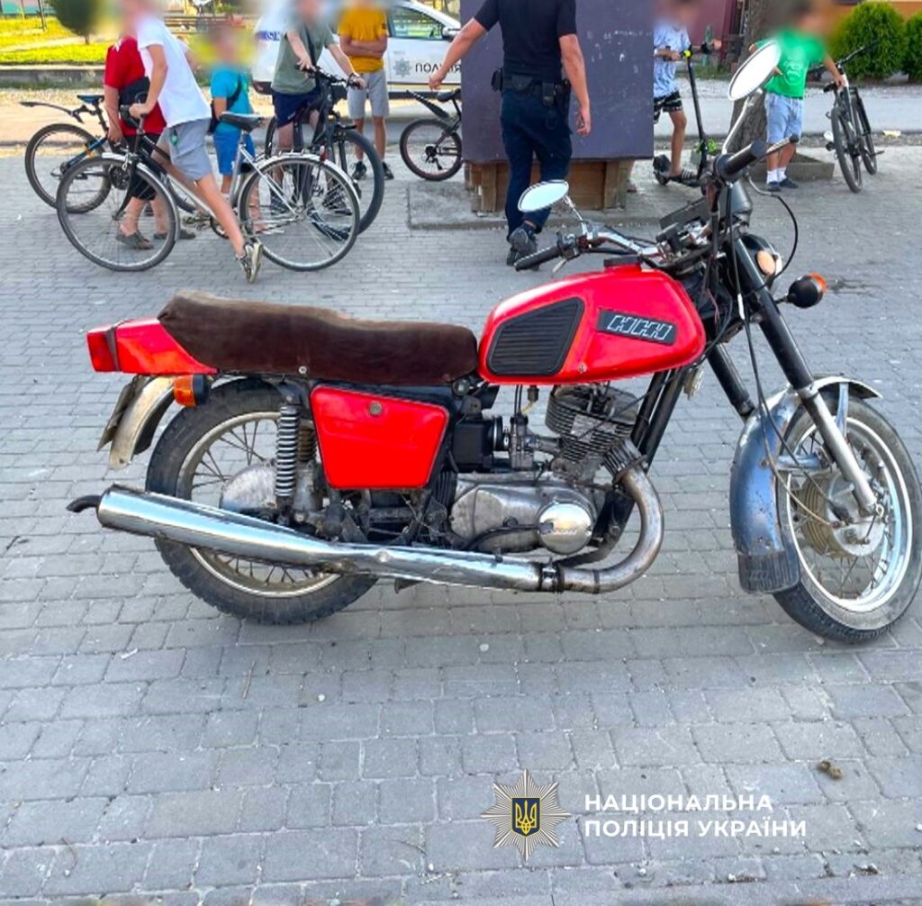 Червоний мотоцикл на міській вулиці, люди поруч.