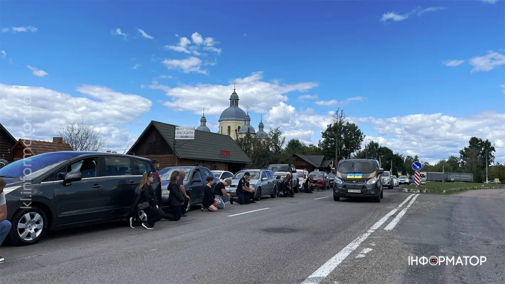 Люди на колінах біля дороги з церквою