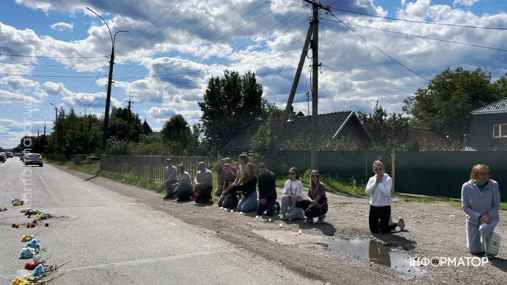 Люди на вулиці стоять на колінах, віддаючи шану.