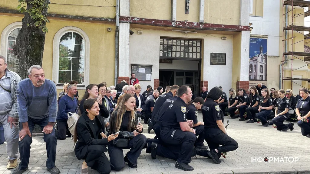 Люди в чорному одязі сидять біля будівлі