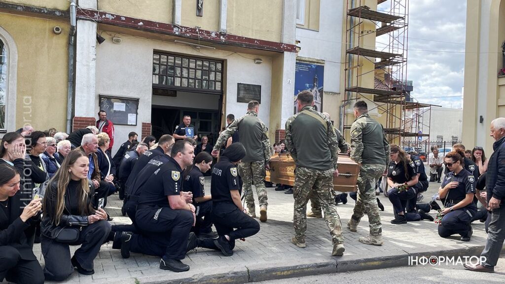 Прощання з військовослужбовцем в Україні, люди на колінах.