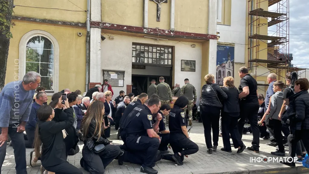 Люди на колінах біля церкви під час служби.