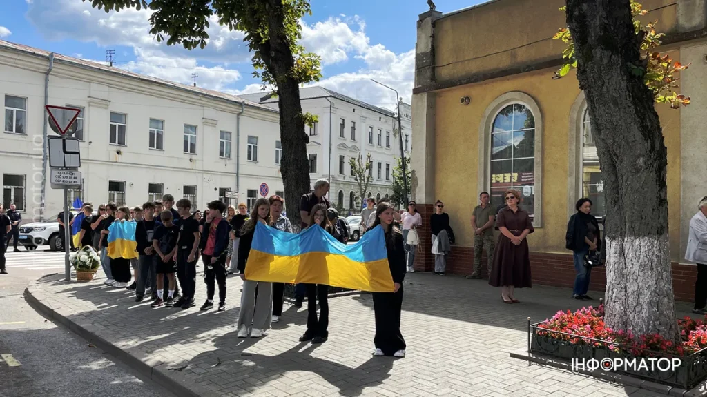 Люди з українськими прапорами на вулиці міста.