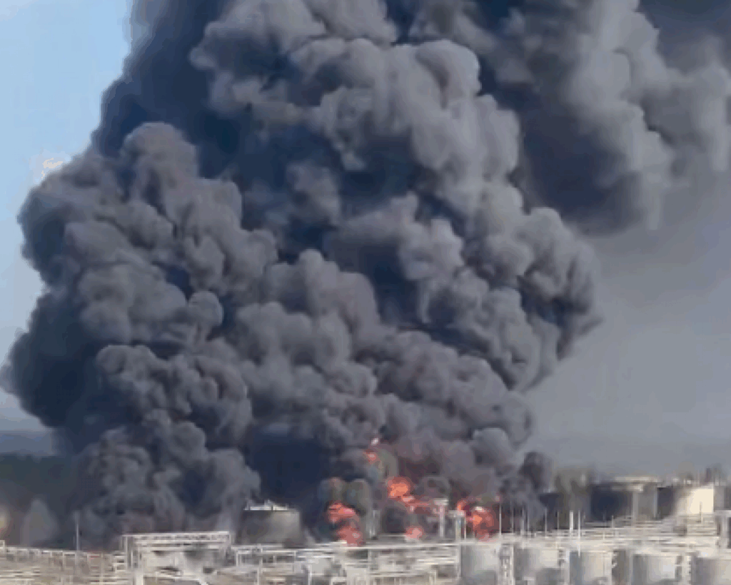 Велика чорна димова хмара над промисловим об'єктом.