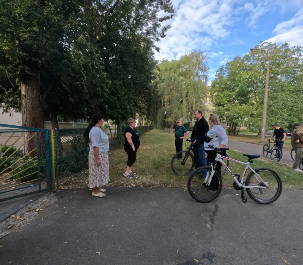 Люди спілкуються на вулиці, поруч велосипеди.