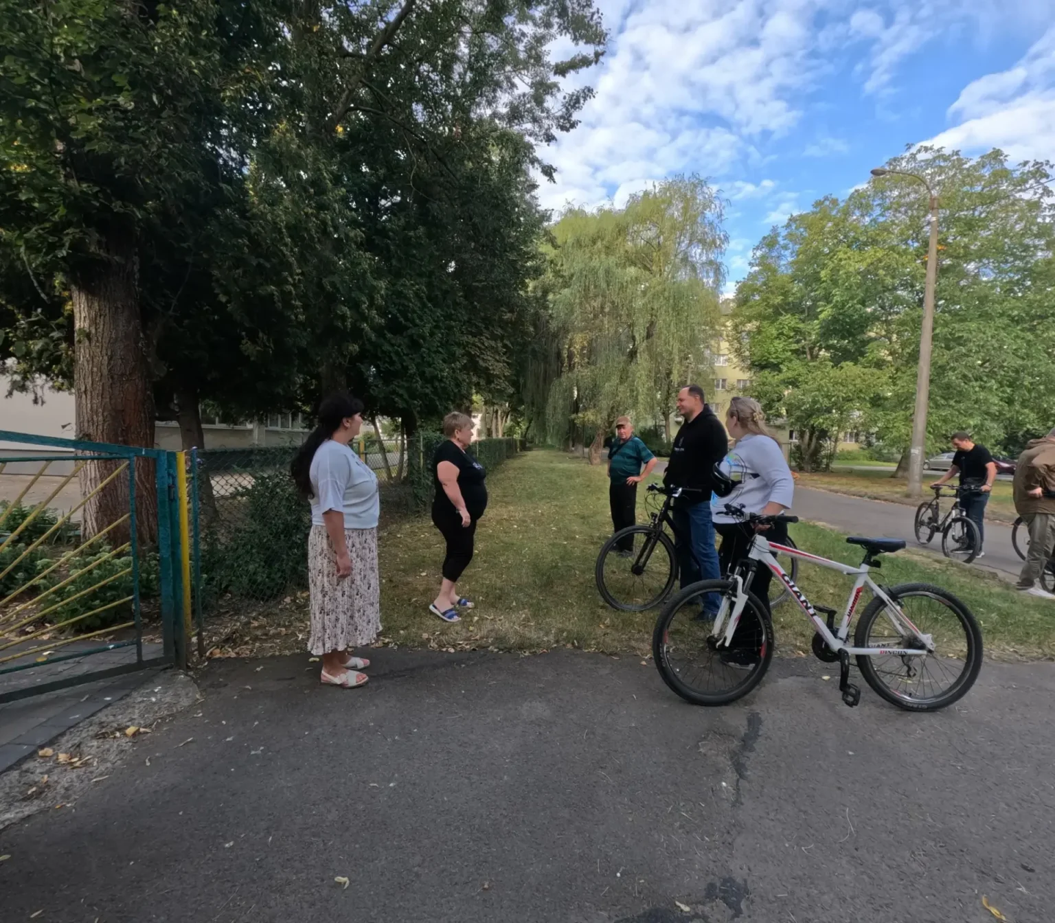 Люди спілкуються на вулиці, поруч велосипеди.