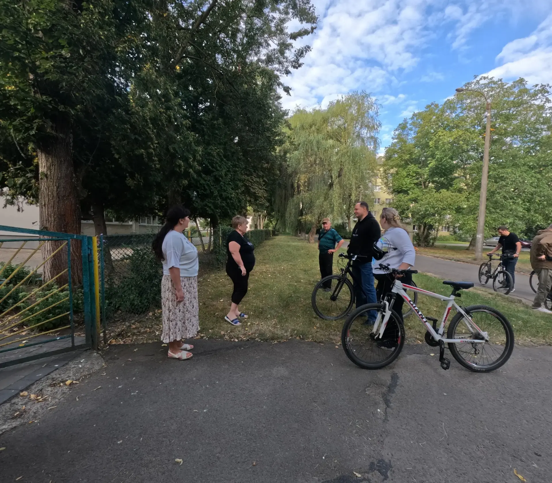 Люди спілкуються на вулиці, поруч велосипеди.
