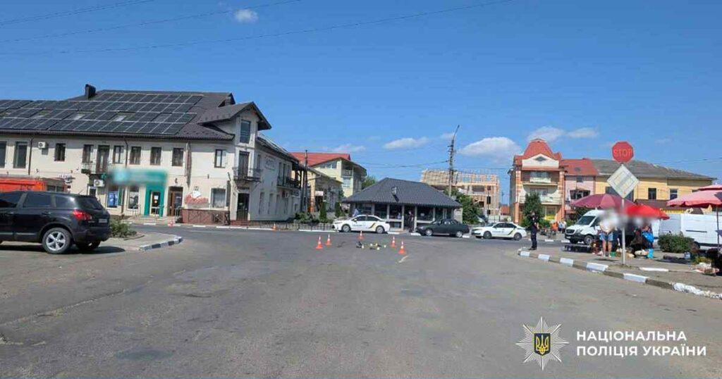 Перехрестя з автівками та будівлями, літній день.