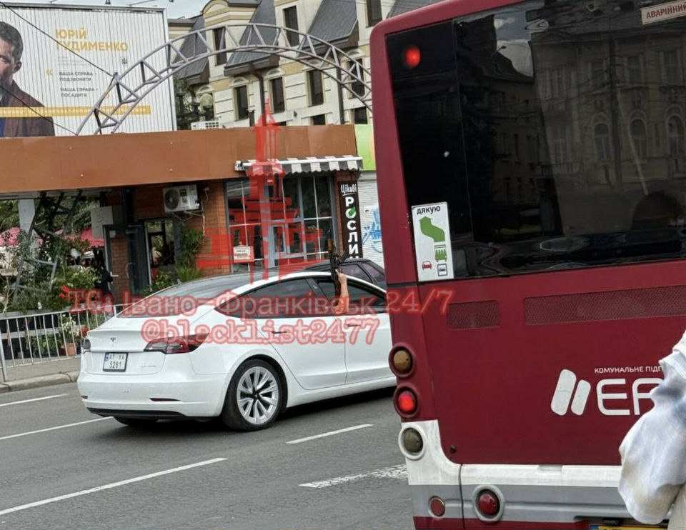 Білий автомобіль позаду червоного автобуса на дорозі