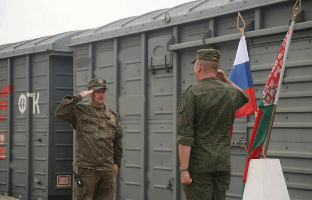 Військові вітають біля поїзда з прапорами.