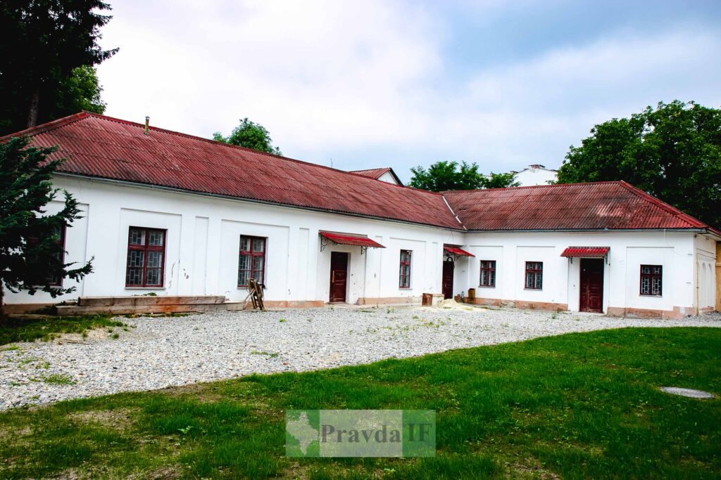 Стара цегляна будівля з червоним дахом і деревами.