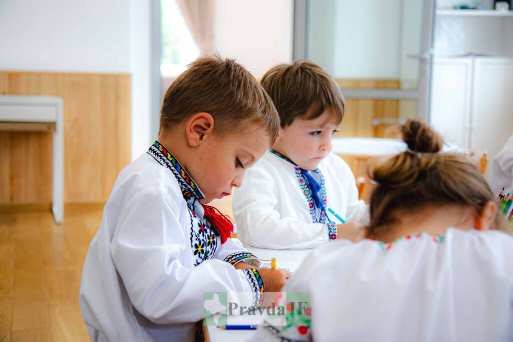 Діти вишивають у вишиванках за столом.