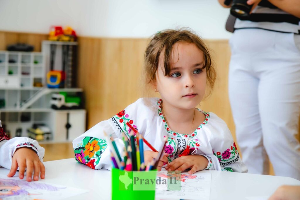Дівчинка вишиванка малює за столом