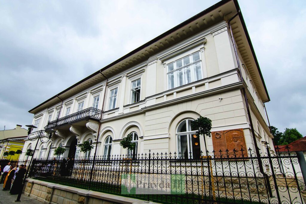 Історична будівля з арочними вікнами та балконом.