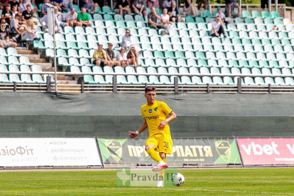 Футболіст у жовтій формі на полі під час гри.