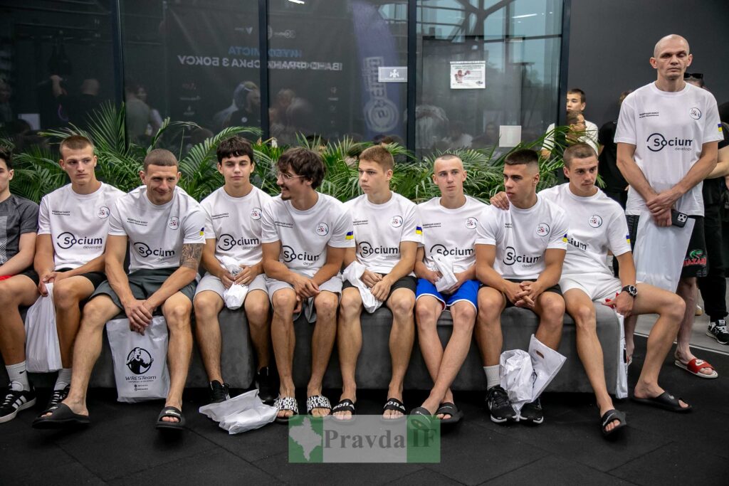 Група молодих спортсменів у спортивній формі сидить.
