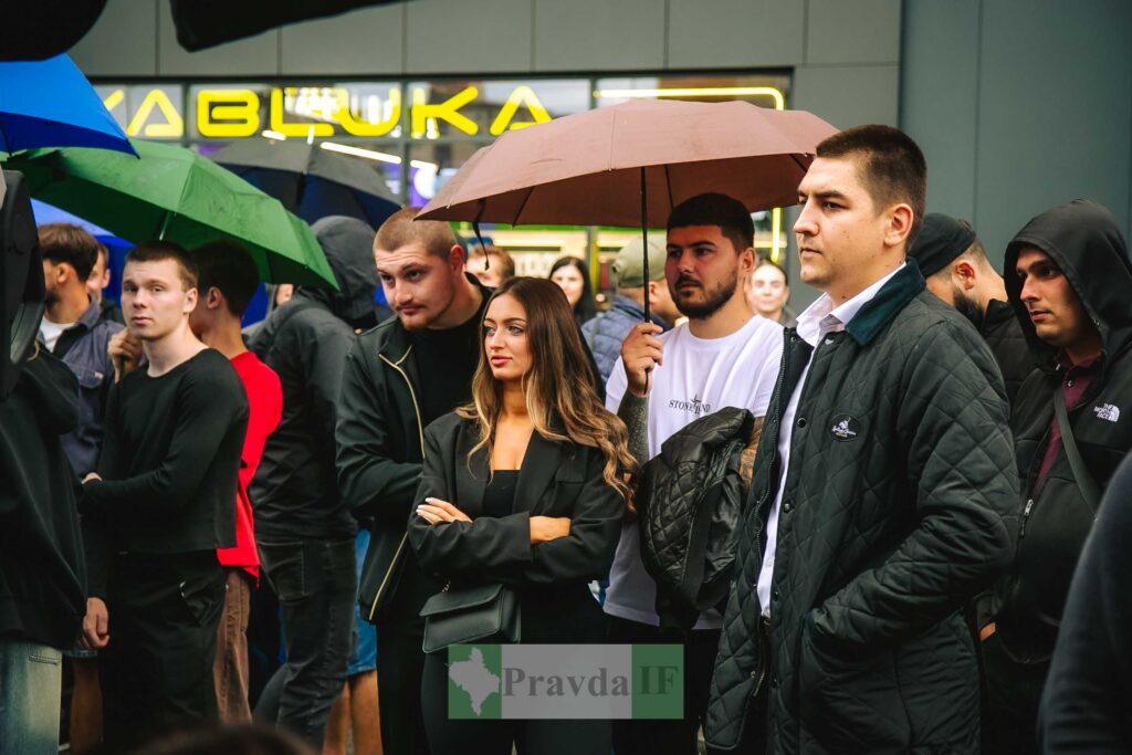 Натовп людей під парасолями на вуличному заході.
